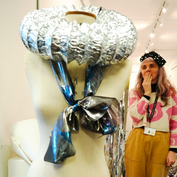 Lecture standing behind a mannequin holding one of the carnival hats