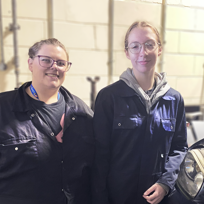 Lily and Sophie standing next to each other in the motor vehicle workshop