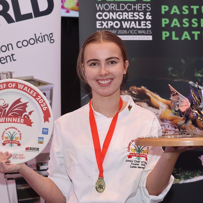 Caitlin Meredith with her medal and award items looking at the camera