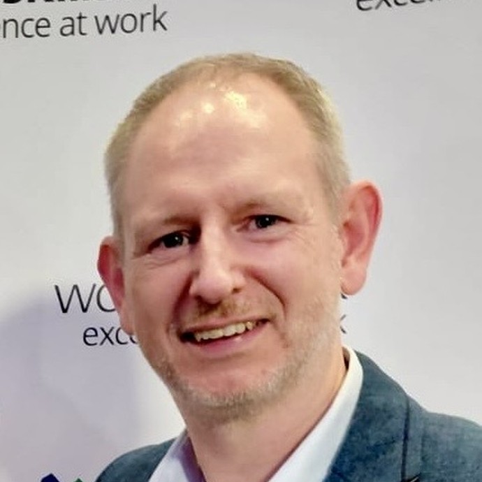 Huw Morgan looking at the camera with WorldSkills branding behind him