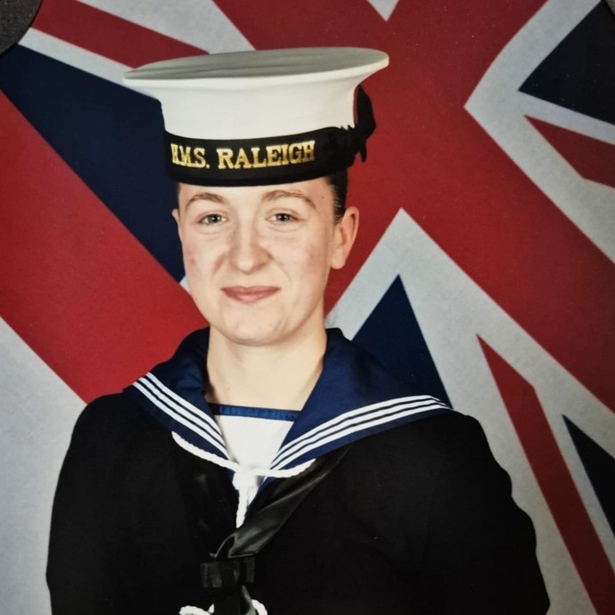 Mia in her Royal Navy uniform in front of the UK flag