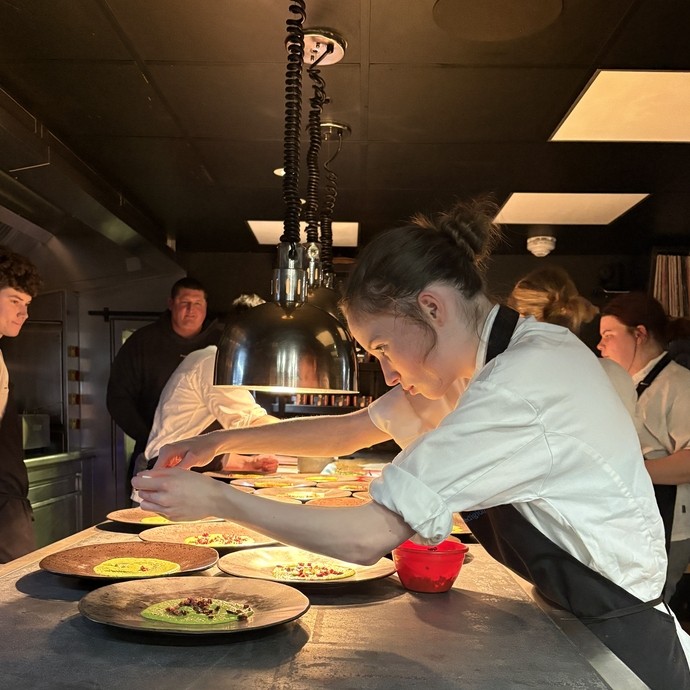 Students at the pass, plating up food with low lighting  